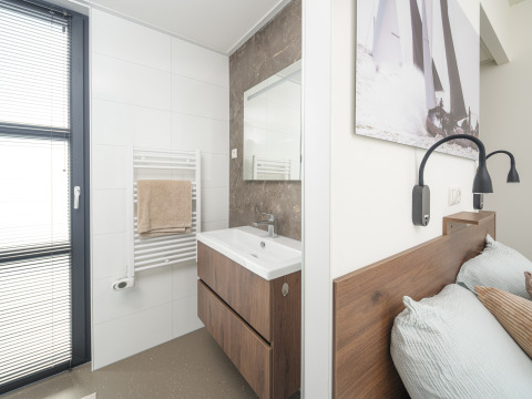 Modern lodge interior showing a bathroom with sink and bedroom area, separated by a partial wall.