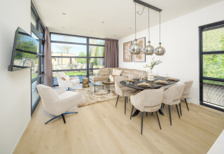 Espace salon et salle à manger contemporain dans un lodge, baigné de lumière avec grandes fenêtres et vue jardin.