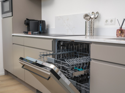 Modern ausgestattete Küche in einer Lodge mit offener Spülmaschine, Kaffeemaschine und Küchenutensilien.