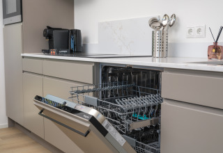 Cuisine moderne dans un lodge avec lave-vaisselle ouvert, appareils électroménagers et ustensiles visibles.