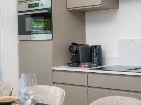 Coin cuisine moderne dans un lodge avec four, machine à café, bouilloire et grille-pain sur le plan de travail.