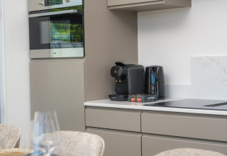 Coin cuisine moderne dans un lodge avec four, machine à café, bouilloire et grille-pain sur le plan de travail.