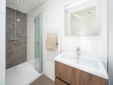 Modernes Badezimmer im Lodge-Stil mit Glasdusche, Holzwaschtisch, Spiegel und Handtuchheizkörper.