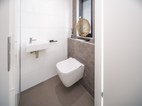 Toilettes de lodge modernes avec WC suspendu, petit lavabo et décoration élégante sur le rebord de fenêtre.
