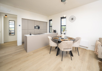 Cocina y comedor de lodge moderno con suelos de madera clara, muebles elegantes y decoración minimalista.