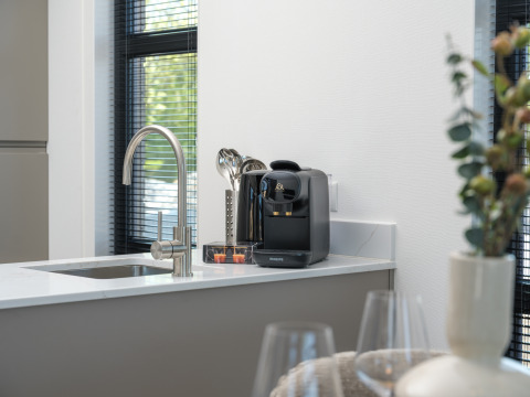Plan de travail de cuisine moderne dans un lodge avec machine à café Philips, évier et décoration élégante.