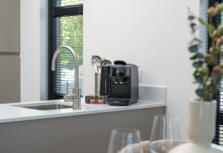 Plan de travail de cuisine moderne dans un lodge avec machine à café Philips, évier et décoration élégante.