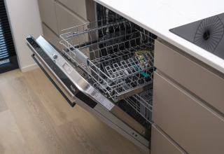 Lavastoviglie aperta in una cucina moderna con pavimento in legno chiaro, fotografata in un lodge.