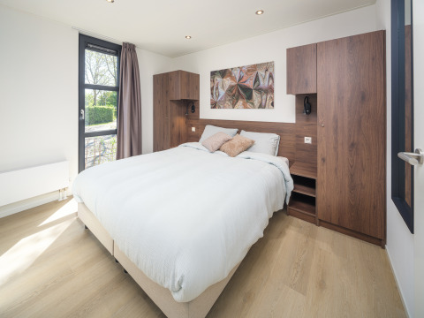 Modernes Lodge-Schlafzimmer mit Doppelbett, Holzmöbeln, großem Fenster und stilvollem Ambiente.