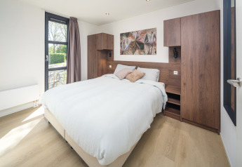 Dormitorio moderno de lodge con cama doble, muebles de madera, ventana grande y decoración minimalista.