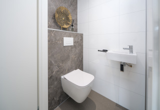 Modernes Lodge-Bad mit wandhängender Toilette, kleinem Waschbecken und stilvoller Dekoration.