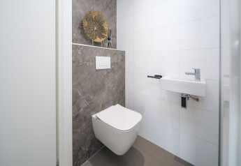 Baño de lodge moderno con inodoro de pared, lavabo compacto y decoración minimalista elegante.
