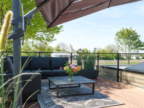 Terrasse sur le toit de la Villa L-Meerzicht avec canapé, parasol et vue dégagée sur la verdure.