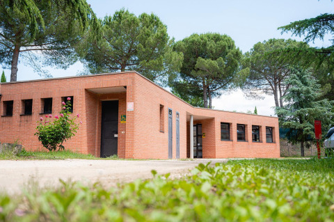 Bâtiment en brique entouré d’arbres à Camping Il Poggetto, Italie, vu de la pelouse au sol.