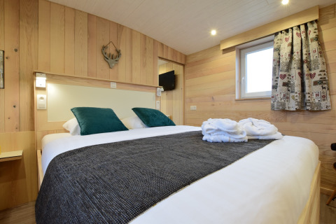 Camera accogliente con pareti in legno e letto matrimoniale a La roulotte des Ardennes in Belgio.