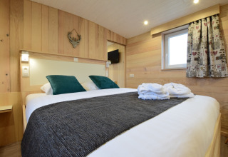 Camera accogliente con pareti in legno e letto matrimoniale a La roulotte des Ardennes in Belgio.