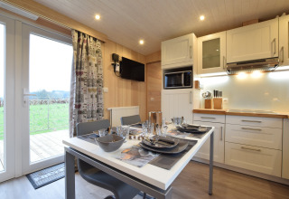 Cucina moderna e zona pranzo a La roulotte des Ardennes, Belgio, con tavolo apparecchiato e vista panoramica.