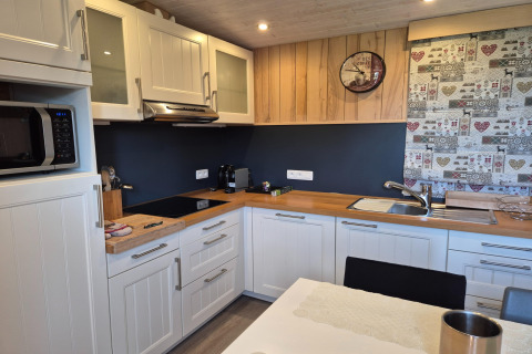 Cucina moderna a La roulotte des Ardennes in Belgio con mobili bianchi e piano in legno.