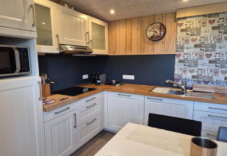 Cucina moderna a La roulotte des Ardennes in Belgio con mobili bianchi e piano in legno.