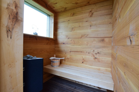 Vista interna di una sauna accogliente con pannelli in legno e panca a La roulotte des Ardennes in Belgio.