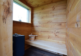 Vista interna di una sauna accogliente con pannelli in legno e panca a La roulotte des Ardennes in Belgio.
