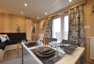 Interno di lodge in legno a La roulotte des Ardennes in Belgio, con tavolo apparecchiato e divano comodo.