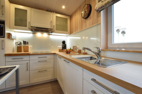 Cucina moderna con mobili bianchi, piani in legno e grande finestra a La roulotte des Ardennes, Belgio.