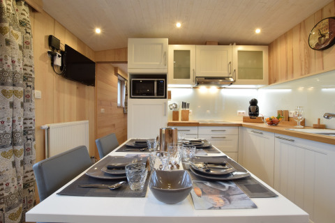 Cucina e zona pranzo moderne presso La roulotte des Ardennes in Belgio con tavolo elegantemente apparecchiato.