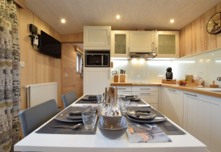 Cucina e zona pranzo moderne presso La roulotte des Ardennes in Belgio con tavolo elegantemente apparecchiato.