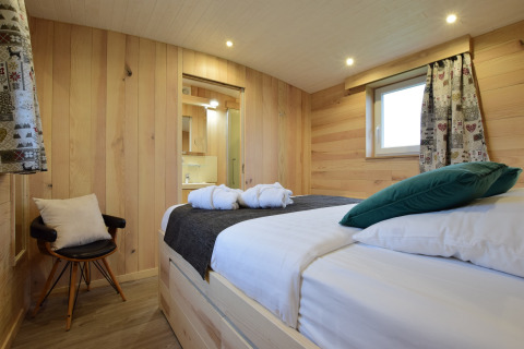 Accogliente camera in legno con letto matrimoniale e bagno a La roulotte des Ardennes, Belgio.