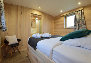 Accogliente camera in legno con letto matrimoniale e bagno a La roulotte des Ardennes, Belgio.