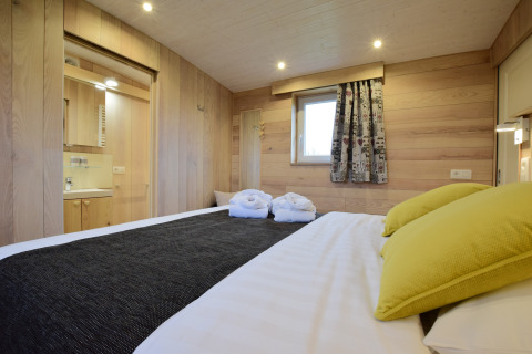 Camera da letto presso La roulotte des Ardennes in Belgio, rivestita in legno e decorazione accogliente.