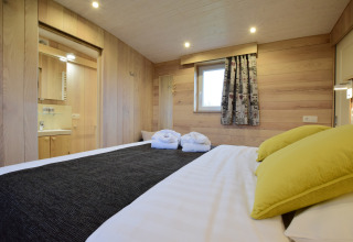 Camera da letto presso La roulotte des Ardennes in Belgio, rivestita in legno e decorazione accogliente.