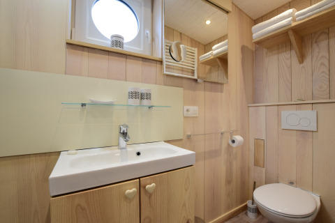 Bagno moderno presso La roulotte des Ardennes in Belgio, con pannelli in legno, lavandino e servizi.