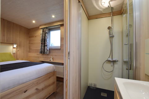 Accogliente camera in legno e doccia moderna nella lodge La roulotte des Ardennes in Belgio.