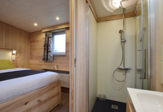 Accogliente camera in legno e doccia moderna nella lodge La roulotte des Ardennes in Belgio.