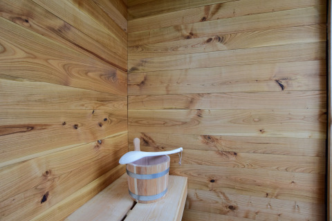 Vista interna di una sauna di legno con secchio e mestolo presso La roulotte des Ardennes, Belgio.