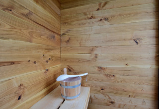Vista interna di una sauna di legno con secchio e mestolo presso La roulotte des Ardennes, Belgio.