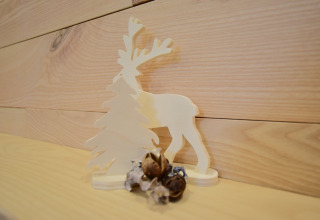 Decorazione in legno con una renna e un albero su una mensola a La roulotte des Ardennes in Belgio.