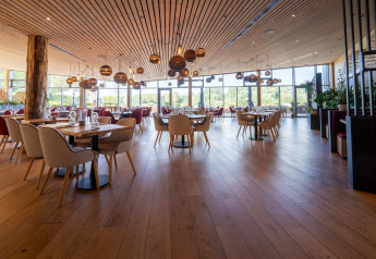 Spacious restaurant with wooden décor, large windows, and elegant seating at a scenic glamping resort.