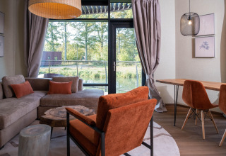 Gezellige glampingruimte met grote ramen, uitzicht op de natuur en stijlvol moderne meubels.