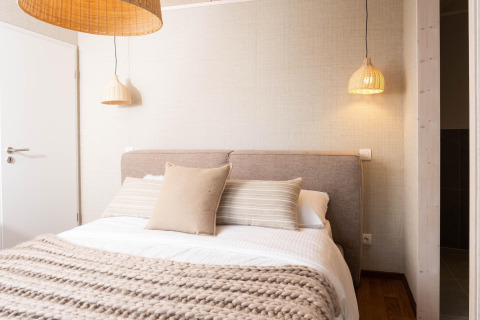 Knusse glamping accommodatie met comfortabel bed, zachte kussens en sfeervolle hanglampen.