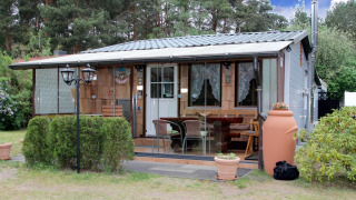 Holiday home Susanne 58 qm with glass patio, outdoor seating, and garden set in a forested area.