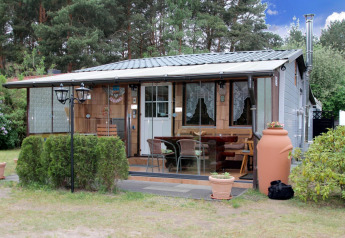 Holiday home Susanne 58 qm with glass patio, outdoor seating, and garden set in a forested area.