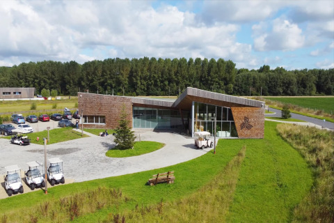 Moderne glamping-accommodatie met houten gevel, golfkarretjes en groene omgeving bij blauwe lucht