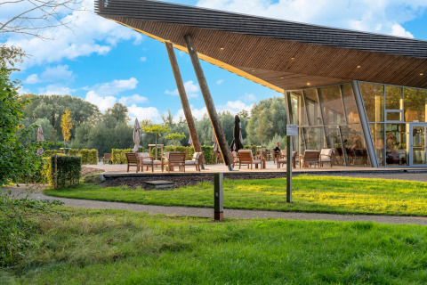 Alojamiento glamping moderno con terraza al aire libre, ventanales grandes y naturaleza exuberante alrededor.