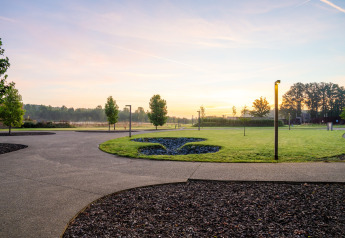 View of a glamping site at sunrise with green lawns, curving pathways, and contemporary outdoor lighting.