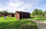 Modern glamping cabins by the lake at The Large Leaf by YourNature with blue sky and green grass.