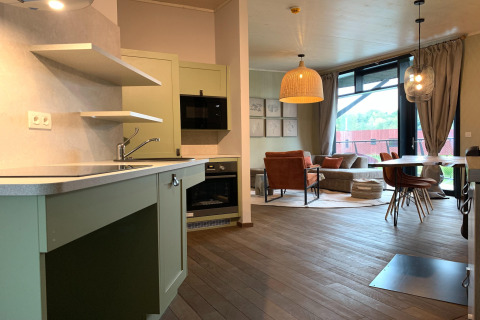 Moderne woonkamer en keuken in The Large Leaf by YourNature lodge met groene kasten en houtaccenten.