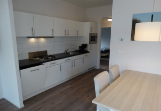 Moderne keuken en eethoek in Breeduyn Village 3 lodge in België met witte kasten en houten tafel.